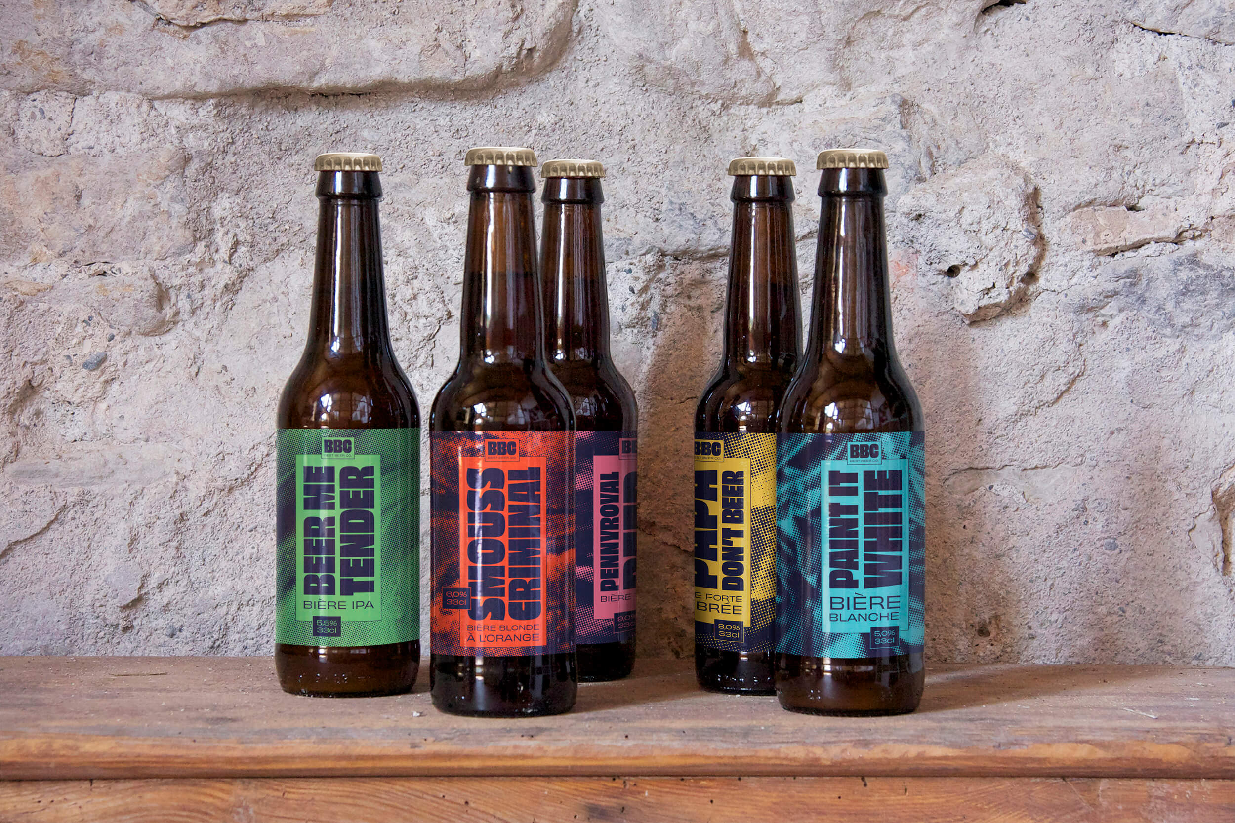 Cinq bouteilles de bière avec des étiquettes colorées.